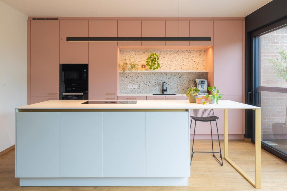 Wit eiland met messing accenten gecombineerd met een warm roze wand met nis voor de spoelbak.